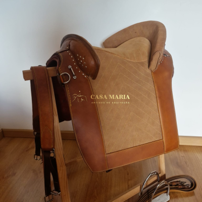 Sela de equitação castanha e bege com textos e acessórios em madeira e couro.