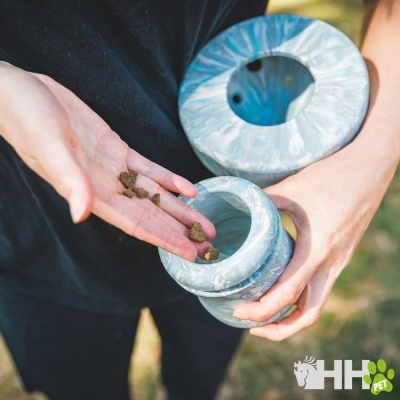 Recipiente cinza marmoreado com ração sendo despejada na mão de pessoa