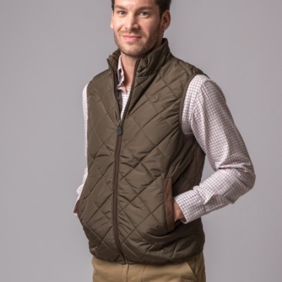 Homem com colete acolchoado verde-oliva sobre camisa quadriculada e calças cáqui