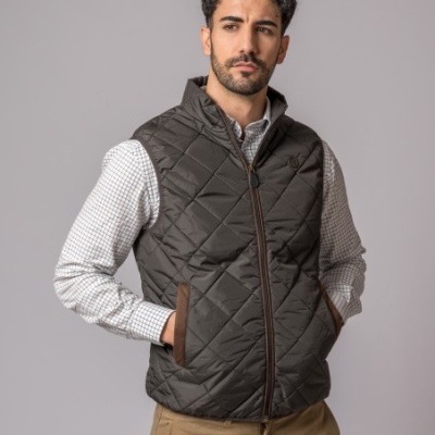 Colete masculino castanho escuro acolchoado com camisa branca e fundo cinzento