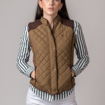 Colete acolchoado castanho feminino com detalhes castanhos escuros, usado com camisa riscada verde e branca e calças brancas
