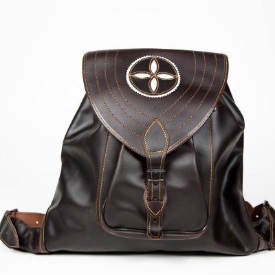 Mochila de couro castanho escuro com fecho e símbolo decorativo