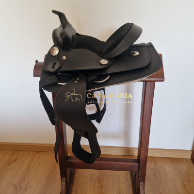 Sela preta de equitação em couro sobre suporte de madeira