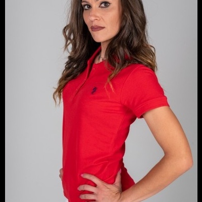 Mulher com polo vermelho de manga curta e calções brancos em fundo cinzento