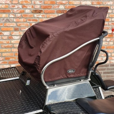 Assento com capa castanha e estrutura metálica contra parede de tijolos