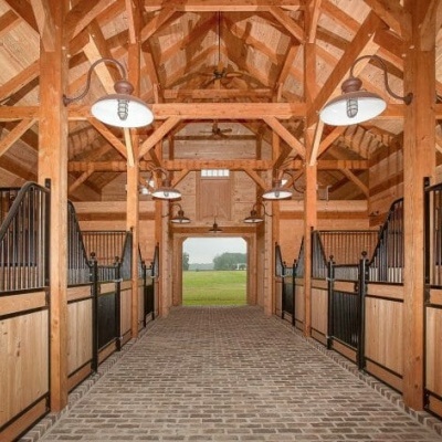 Interior de estábulo em madeira com boxes e chão em tijoleira