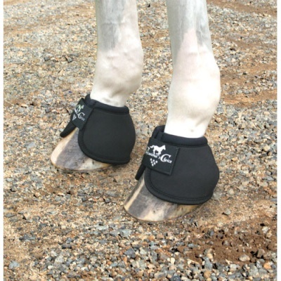 Patas de cavalo com protetores pretos e velcro sobre cascalho