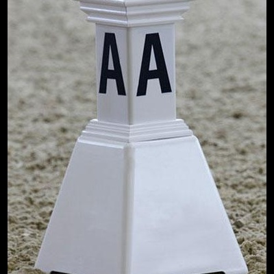 Peça branca com letras 'AA' em preto sobre superfície de areia