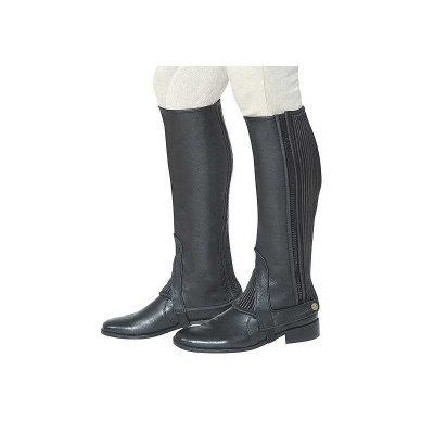 Botas pretas de montaria em couro com elásticos na parte traseira usadas com calças claras.