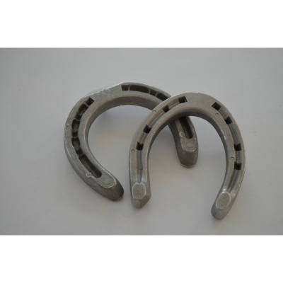 Duas ferraduras metálicas prateadas sobre superfície branca