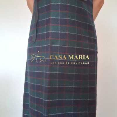 Saia xadrez comprida com laço preto na cintura, usada com camisola polo vermelha