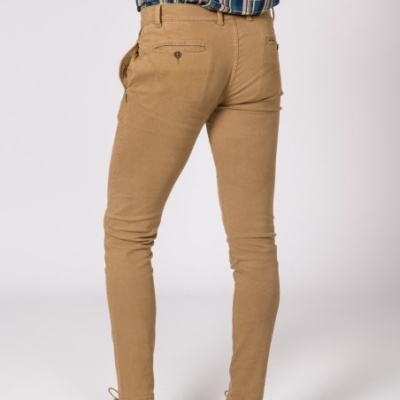 Pessoa vista de costas usando calças bege slim fit, camisa xadrez azul e verde, sapatos castanhos com sola azul.