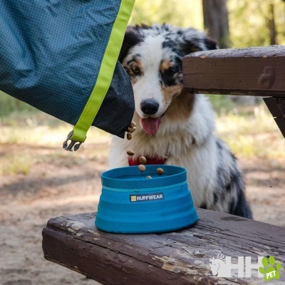 Cão ao ar livre com comedouro azul RUFFWEAR e saco de ração verde