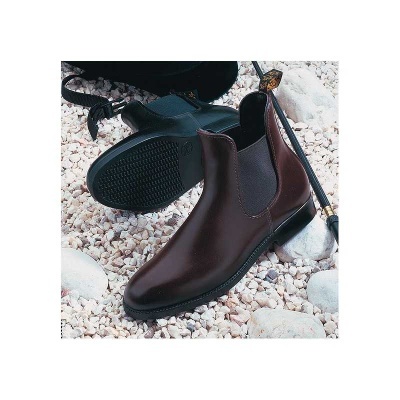 Botas Chelsea de pele castanha com sola preta sobre cascalho