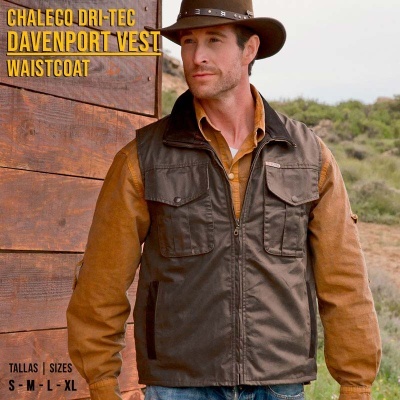 Colete castanho escuro masculino com bolsos e fecho, usado sobre camisa castanha num cenário natural.