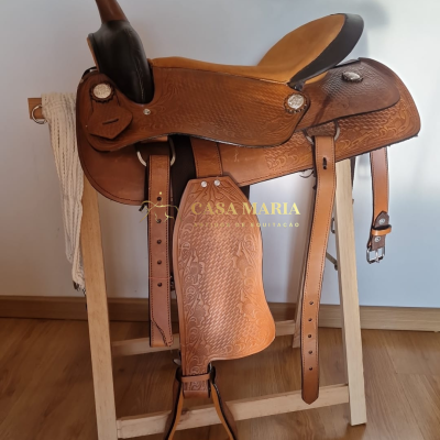 Sela de montaria em couro castanho claro detalhado num suporte de madeira