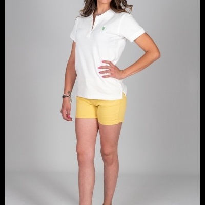 Mulher com polo branca, calções amarelos e sandálias castanhas.