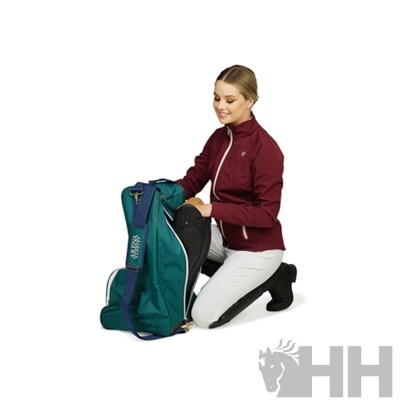 Mulher agachada com mochila verde-azulada e jaqueta bordô