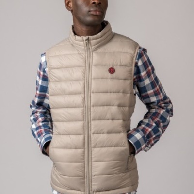 Homem a usar colete acolchoado bege com camisa xadrez e calças de ganga