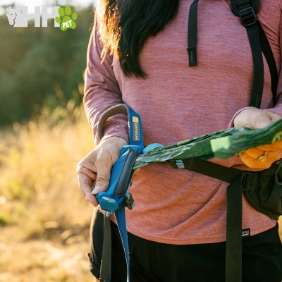 Pessoa a segurar brinquedo canino azul e verde ao ar livre com logótipo HIPET