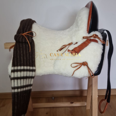 Sela de equitação branca com detalhes em couro castanho e preto sobre suporte de madeira