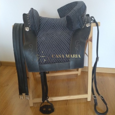 Sela de equitação cinzenta riscada com detalhes em couro preto e rédeas pretas num suporte de madeira
