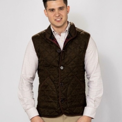 Homem com colete castanho acolchoado e camisa xadrez branca com vermelho