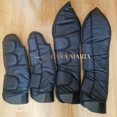 Protetores pretos acolchoados para pernas de cavalo com fechos de velcro sobre chão de madeira clara