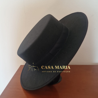 Chapéu preto com aba larga e fita preta sobre mesa de madeira