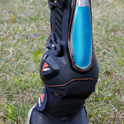 Protetor para perna de cavalo preto com detalhe azul translúcido e fivelas, em relva