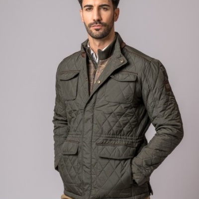 Casaco masculino acolchoado verde-oliva com bolsos e botões, usado por modelo de pé com fundo cinza claro.