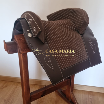 Sela de equitação castanha de couro e camurça num suporte de madeira