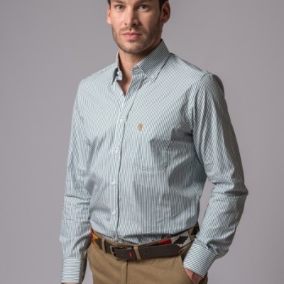 Homem a vestir camisa riscada azul clara, calças bege e cinto castanho