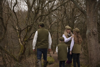 Quatro pessoas com coletes verdes e camisas xadrez em floresta sem folhas