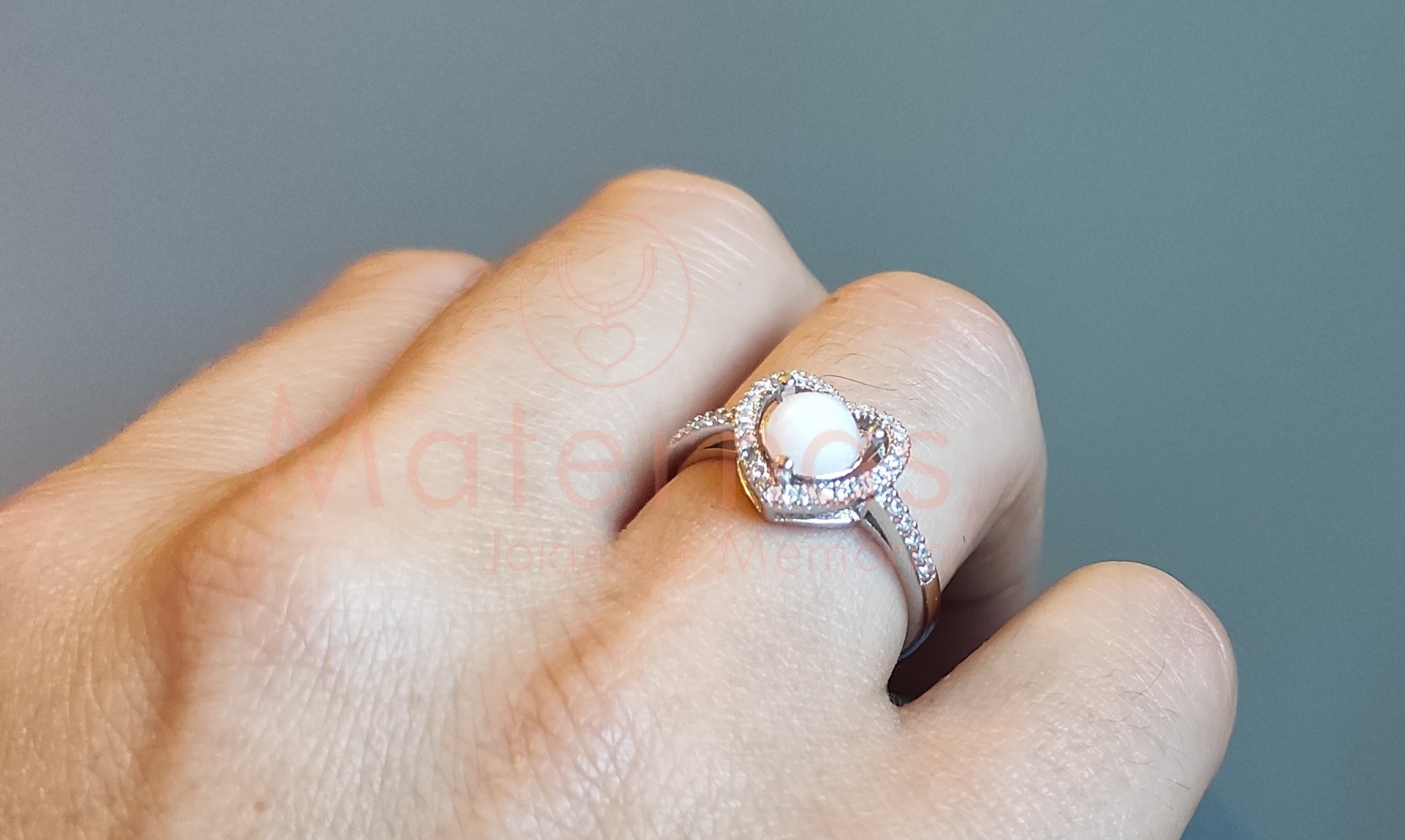 Anel Coração Alto Anel prateado com pérola branca central e brilhantes num dedo