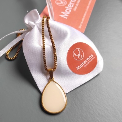 Colar dourado com pendente gota creme sobre saco branco com etiqueta Maternas