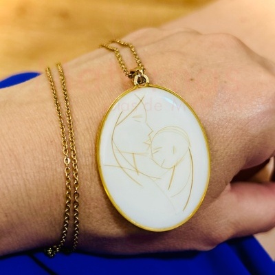 Colar com pendente oval branco e dourado com desenho de mãe a beijar bebé