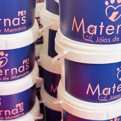 Baldes plásticos pintados de azul com tampa branca e texto cor de rosa empilhados.