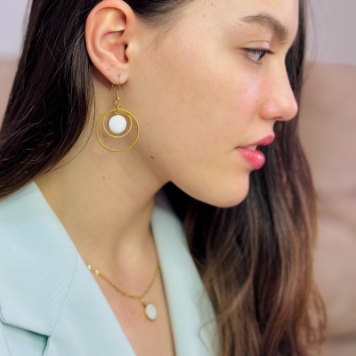 Brincos dourados com esfera branca em modelo