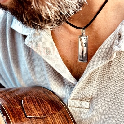 Colar metálico prateado com cordão preto usado por homem