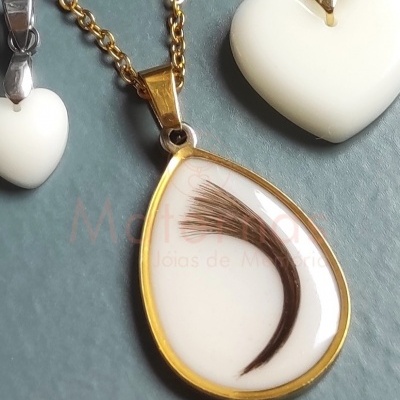 Colares com pendentes em forma de gota e corações brancos sobre fundo cinzento