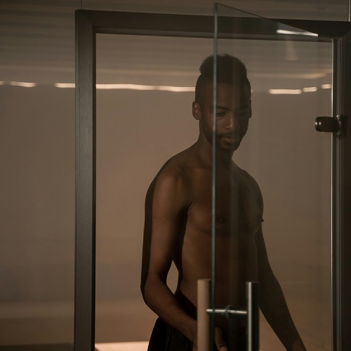 Homem nu dentro de chuveiro com porta de vidro