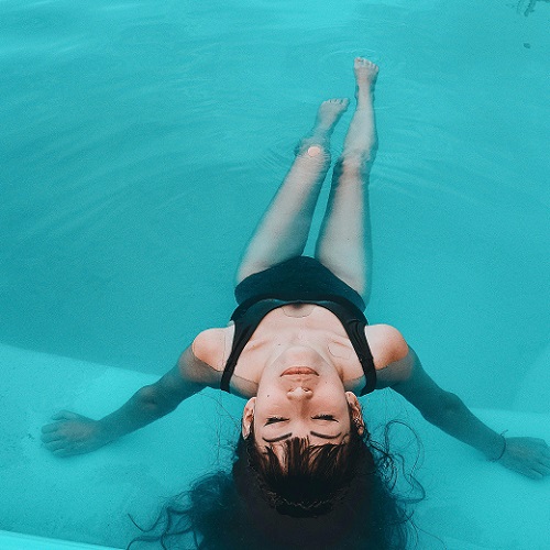 Pessoa deitada de costas em piscina com fato de banho preto