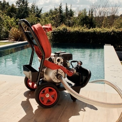 bomba de água portátil preta e vermelha junto a uma piscina