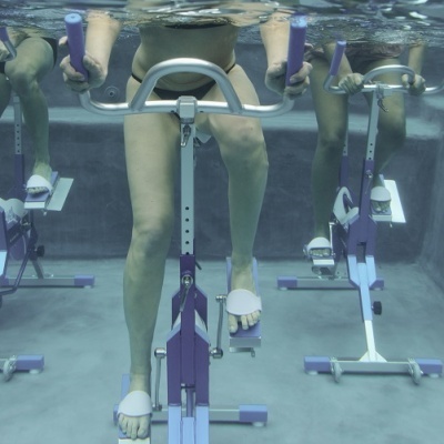 Bicicletas estáticas subaquáticas púrpura e branca numa piscina