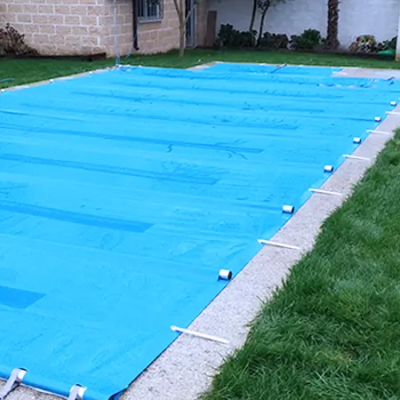 Cobertura azul para piscina com fixações brancas numa piscina ao ar livre