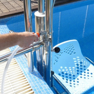 Torneira metálica sendo ajustada ao lado de piscina com escada branca