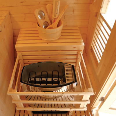 Interior de sauna em madeira com banco, caldeira metálica e balde de madeira com utensílios