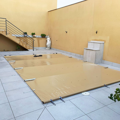 Cobertura beje de piscina retangular numa área exterior com chão cinzento e parede amarela
