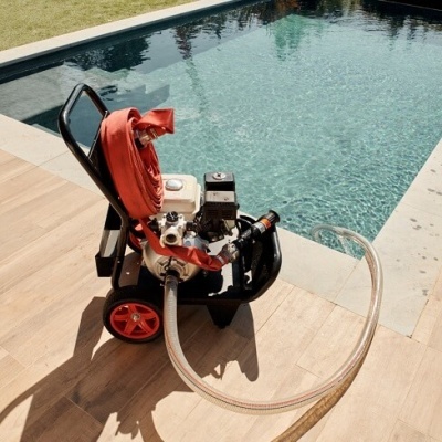 Máquina portátil com mangueiras e rodas vermelhas junto a piscina